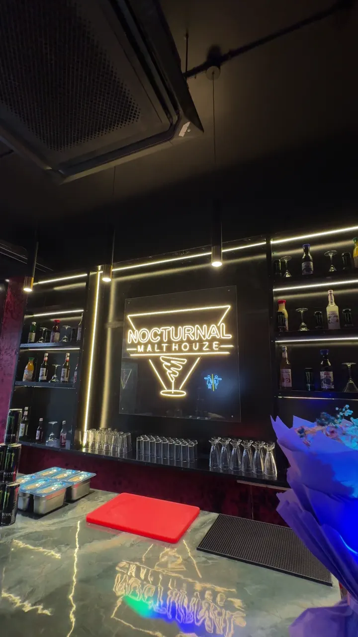 The lounge under blue light beams, red textured walls and dark booths