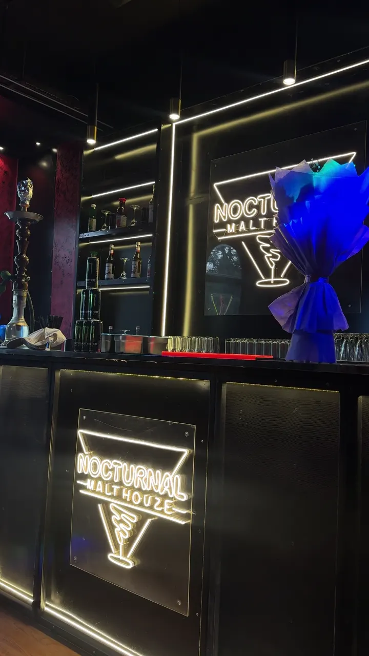 The illuminated Nocturnal Malt Houze sign behind the bar
