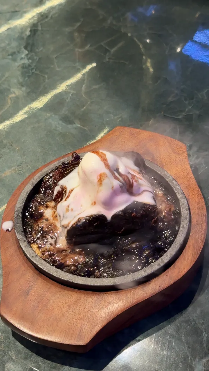 A brownie with ice cream sizzling on a hot iron plate
