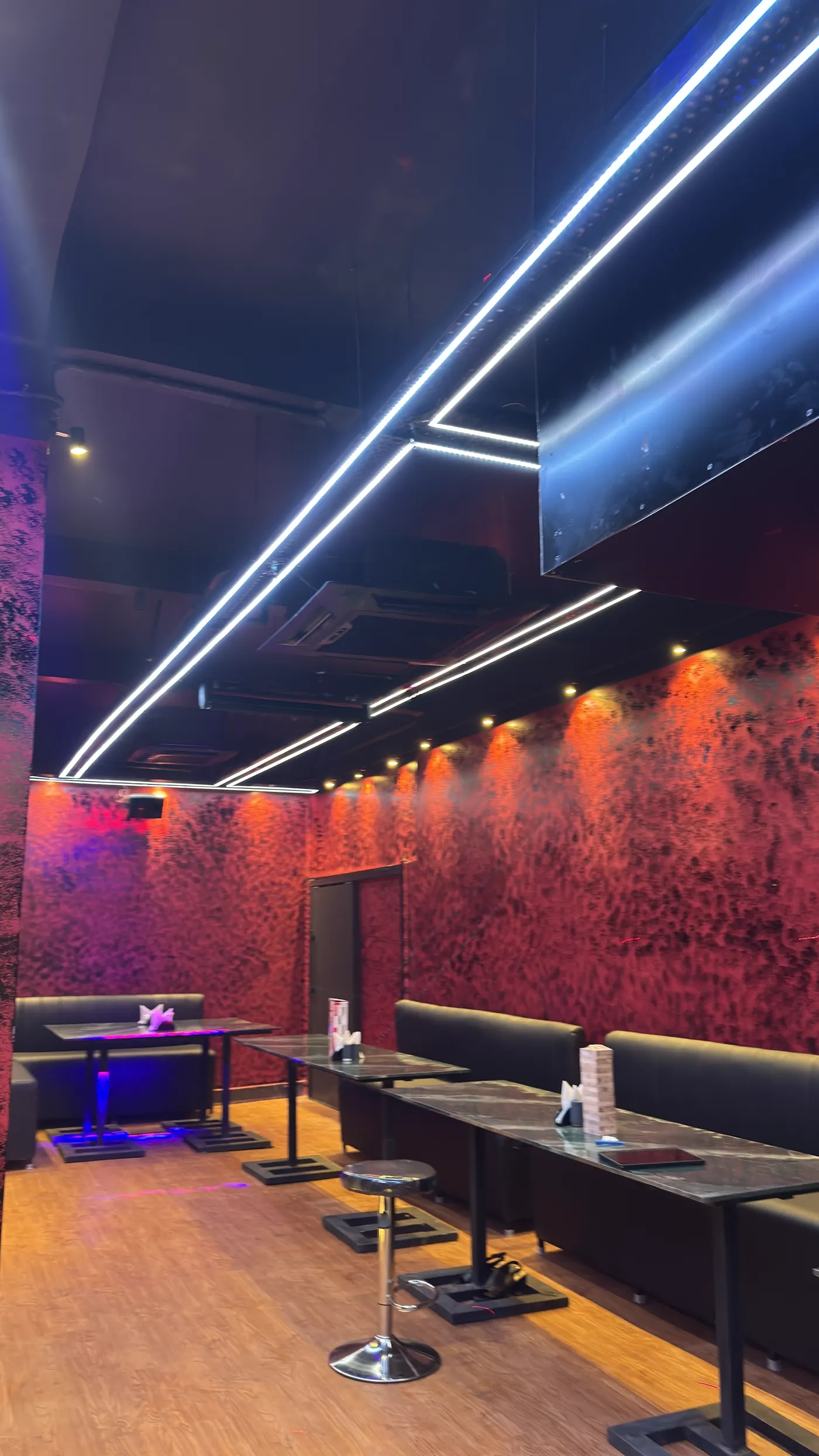 Long view of the lounge with red walls and coloured floor lights
