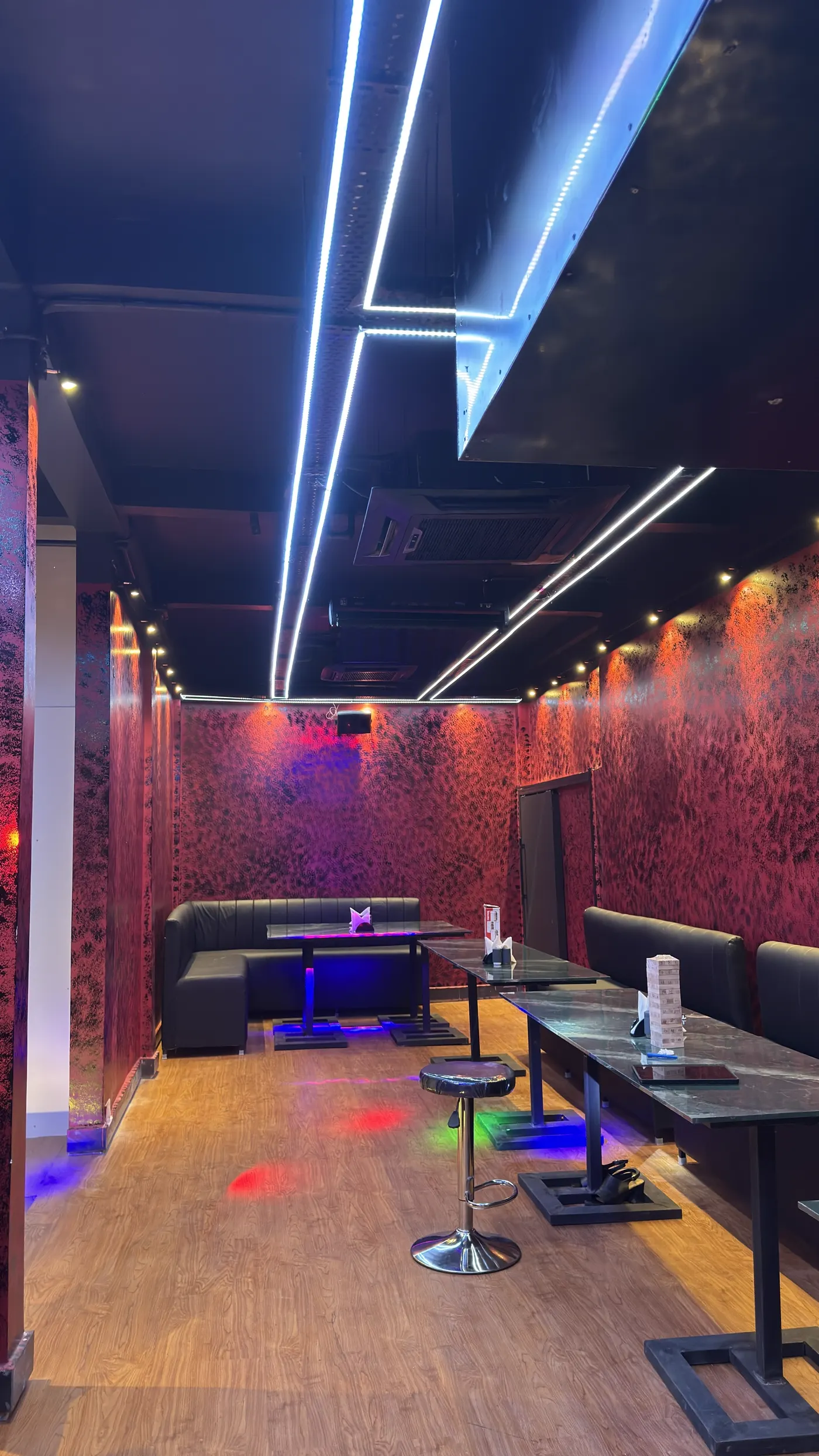 The dining room with booths under ceiling light lines and red walls